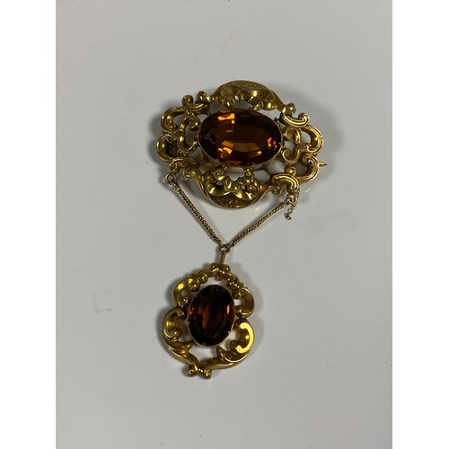 87 - A 19th century repousse brooch, set with an oval citrine suspending a similar pendant drop -