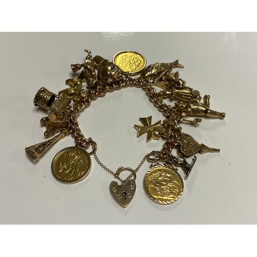 A heavy 9ct gold charm bracelet, suspending an array of charms, a 1900 sovereign, a 1928 sovereign and a Georgian spade guinea -