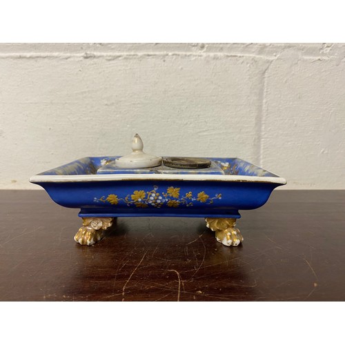 112 - A 19th century porcelain inkwell, painted with panels of flowers and gilt vines on a blue ground -