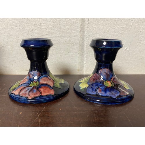 113 - Moorcroft:  A pair of clematis pattern candlesticks, impressed marks and paper label to each -