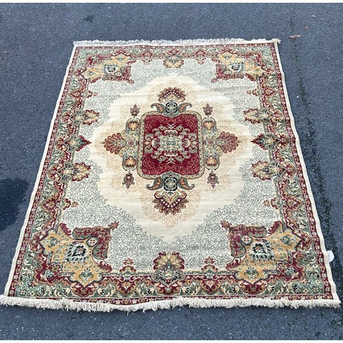 358 - A large wool rug worked with a central motif on red and cream ground (approximately 280x200cm) -