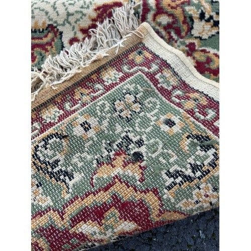 358 - A large wool rug worked with a central motif on red and cream ground (approximately 280x200cm) -