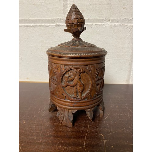 101 - A Scandinavian folk art circular box and cover, carved in the round with figures, on leaf support -