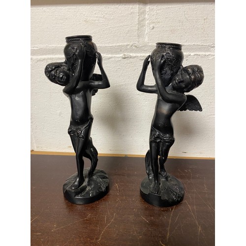 102 - A pair of classical style bronze candlesticks, each with an angel holding an urn -