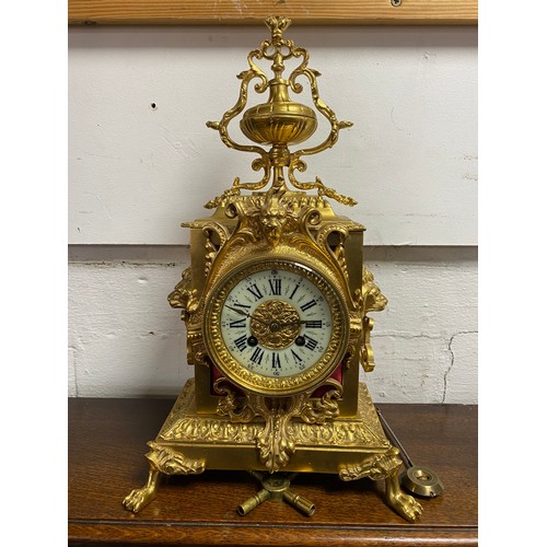 368 - A gilt cased mantel clock, surrounded by a classical urn, with lion masks above dial, lion mask and ... 