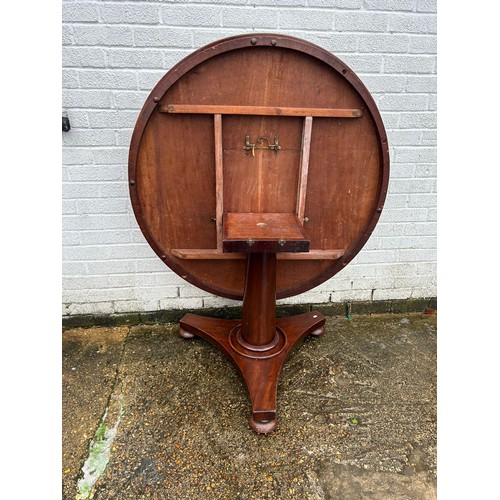 397 - A Victorian mahogony dining table, the circular tilt top on centre pillar and triform base -