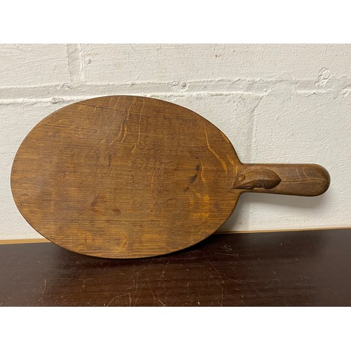 107 - Mouseman: A Robert Thompson oak cheeseboard, the handle carved with typical mouse -