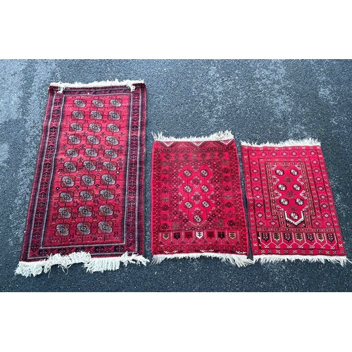 420 - A group of three rugs, each worked on a red ground -