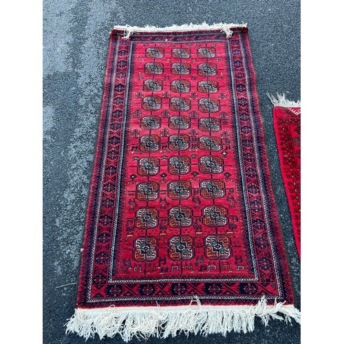 420 - A group of three rugs, each worked on a red ground -