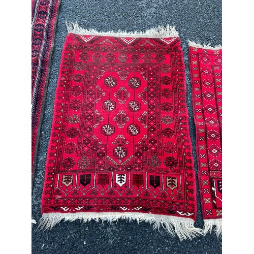 420 - A group of three rugs, each worked on a red ground -