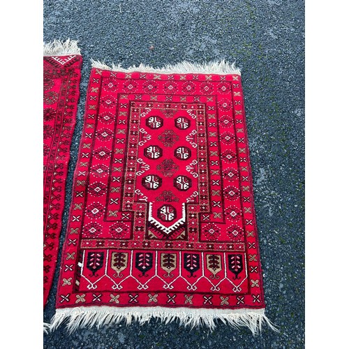 420 - A group of three rugs, each worked on a red ground -