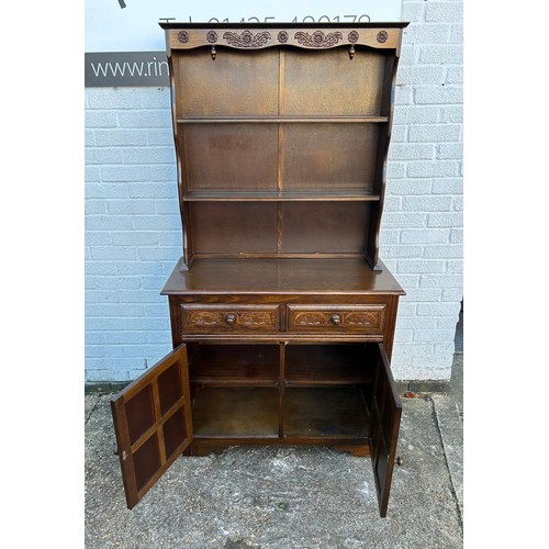 425 - An oak dresser, of narrow size, with shelved top over two drawers and cupboard doors -