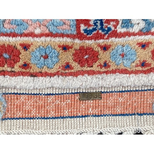 285 - A Turkish wool rug worked with a geometric detail on a cream, red and blue ground, approximately 190... 