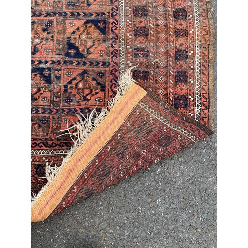 286 - A wool rug , worked with a central panel of geometric detail on a red and blue ground approximately ... 