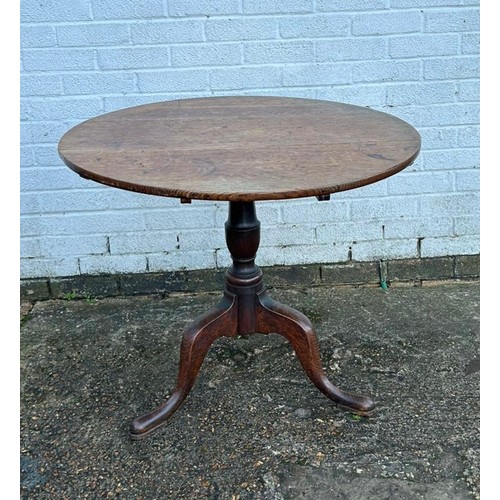 304 - A 19th Century oak tilt top table, with circular top on central support on three legs -