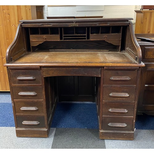 331 - An oak roll top desk, fitted with an arrangement of pigeon holes and drawers over nine drawers -