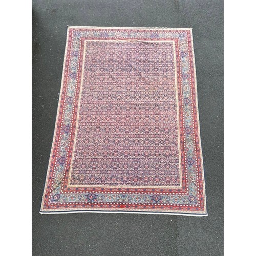 A large eastern rug , worked on a red and blue ground, approximately 400cm x 277cm -