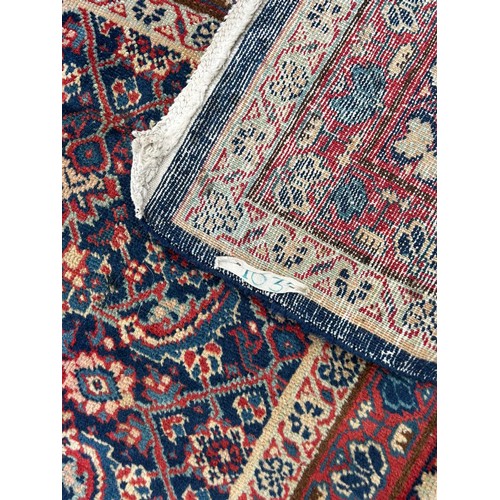 349 - A large eastern rug , worked on a red and blue ground, approximately 400cm x 277cm -