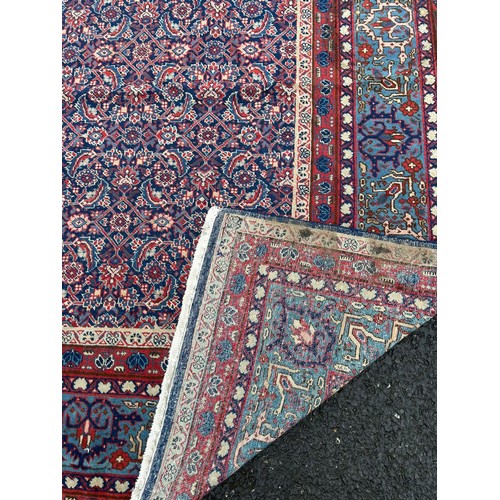 349 - A large eastern rug , worked on a red and blue ground, approximately 400cm x 277cm -