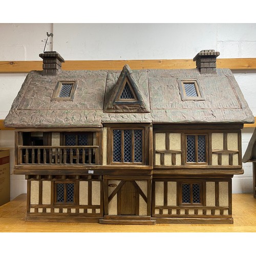 A Robert Stubbs 'Radnor Hall' dolls house, designed as a three storey Tudor building, with eight lift off sections to reveal individual room settings, with associated fixtures, fittings and furnishings, dolls and certificate -