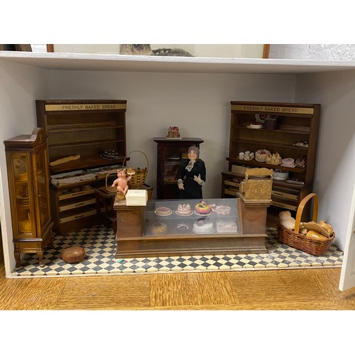 249 - A vintage dolls house, designed as a shop, with bow fronted window and door, with bakery accessories... 