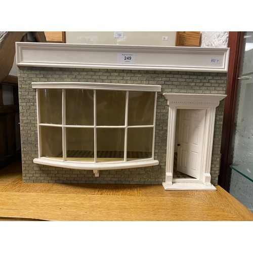 249 - A vintage dolls house, designed as a shop, with bow fronted window and door, with bakery accessories... 