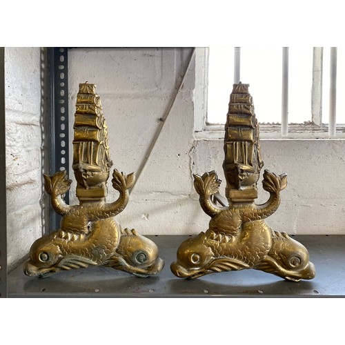 A pair of brass fire andirons designed as a galleon and dolphins -