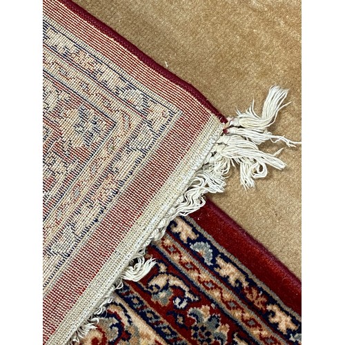 395 - An eastern wool rug, worked with central motif on a red ground within cream and red guard stripes, a... 