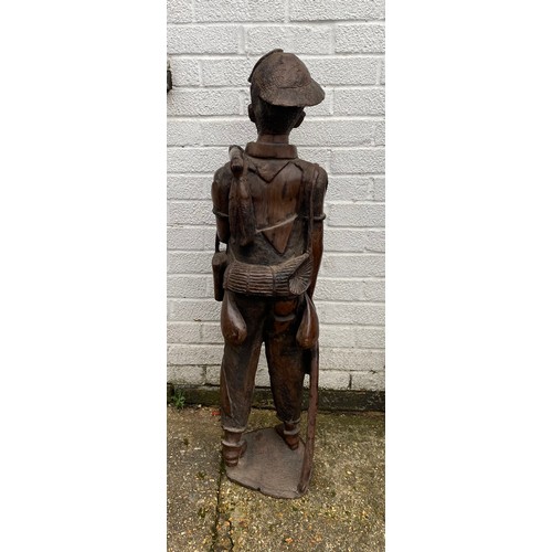 171 - A large Indonesian carved hardwood figure, naturalistically carved as a standing fisherman -