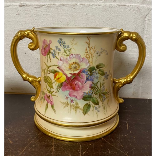 240 - A large Royal Worcester two handled loving cup, painted with flowers on a blush ground, with gilded ... 