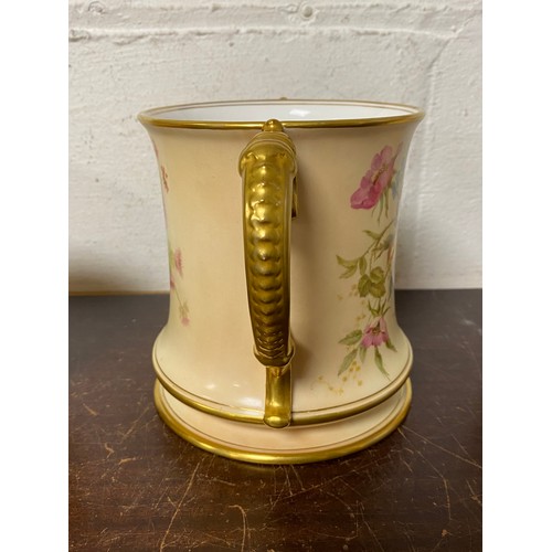 240 - A large Royal Worcester two handled loving cup, painted with flowers on a blush ground, with gilded ... 