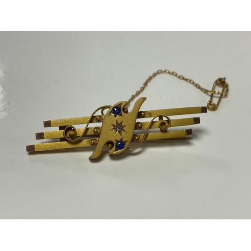 140 - An early 20th Century 9ct gold bar brooch, set with sapphires and a diamond point -