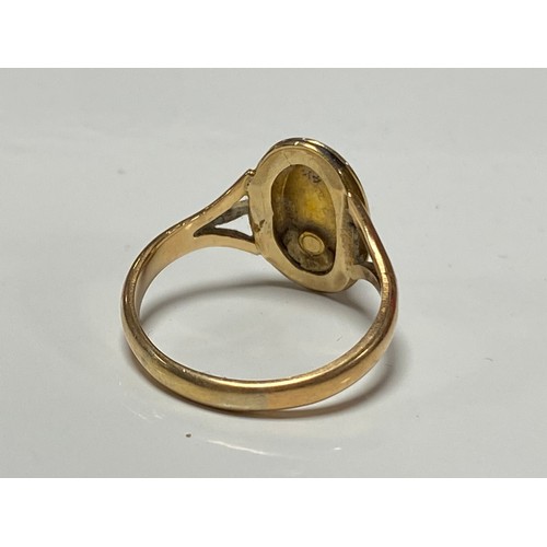 169 - A yellow metal dress ring, set with an oval tigers eye cabouchon -
