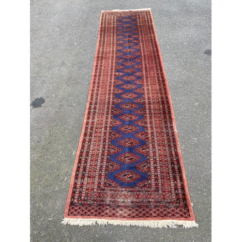 An eastern runner, worked with motifs on a blue ground between red and chevron guard stripes, approximately 360 x 95cm -