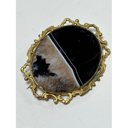 43 - A Victorian agate brooch, the agate slice in scrollwork frame -