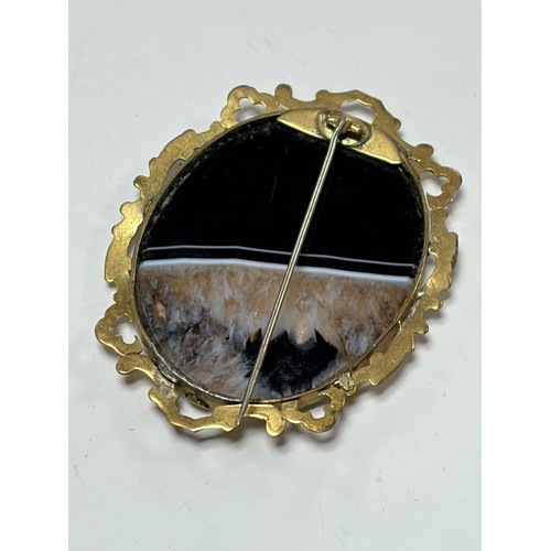 43 - A Victorian agate brooch, the agate slice in scrollwork frame -