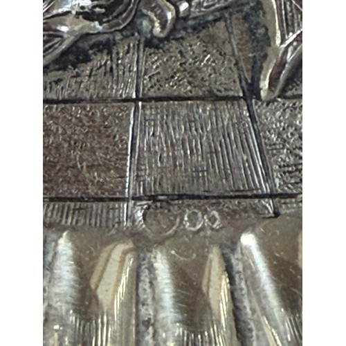 53 - A white metal dish, with repousse landscape detail and pierced surround, together with a silver spoo... 