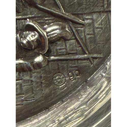 53 - A white metal dish, with repousse landscape detail and pierced surround, together with a silver spoo... 