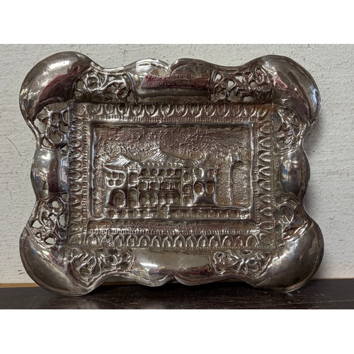 53 - A white metal dish, with repousse landscape detail and pierced surround, together with a silver spoo... 
