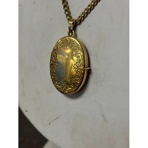 59 - A 9ct gold locket, with scrolled decoration, to a 9ct gold chain -