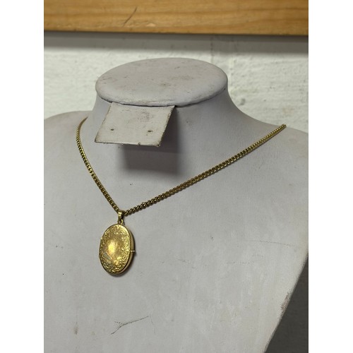 59 - A 9ct gold locket, with scrolled decoration, to a 9ct gold chain -