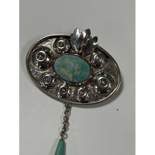 67 - An Arts and Crafts silver brooch. the oval panel with blue hardstone panel in textured mount, with d... 