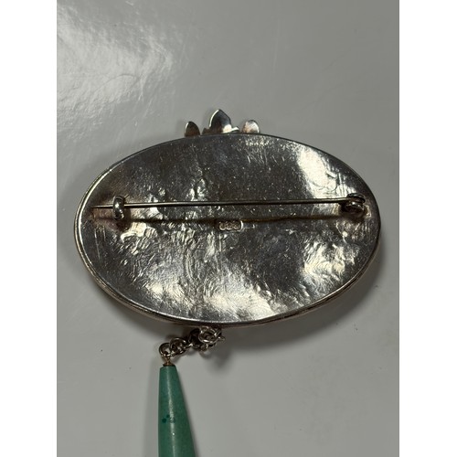 67 - An Arts and Crafts silver brooch. the oval panel with blue hardstone panel in textured mount, with d... 