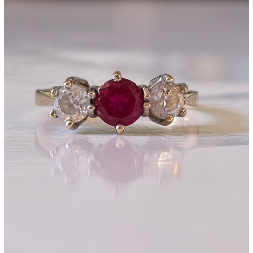 12 - A clear and ruby coloured CZ set three stone ring, set in 14ct gold -