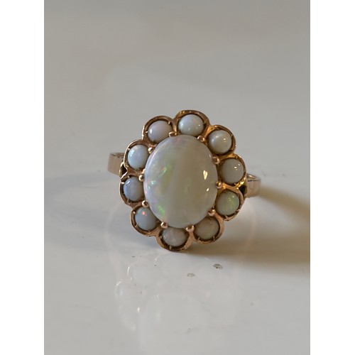 29 - An opal dress ring, of oval cluster design, set in yellow metal mount, stamped 585 -