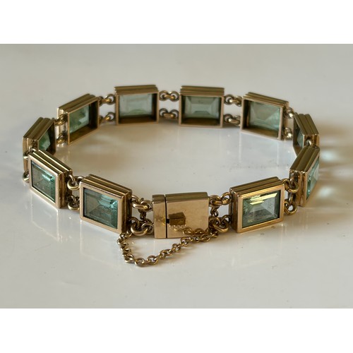 30 - A gem set bracelet, set with rectangular green stones in yellow metal mount -
