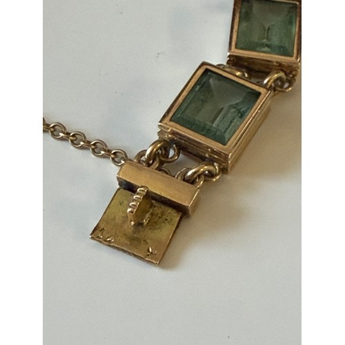 30 - A gem set bracelet, set with rectangular green stones in yellow metal mount -