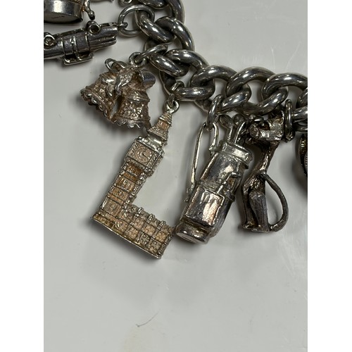 41 - A heavy silver charm bracelet, suspending an array of charms, including Big Ben and a top hat -