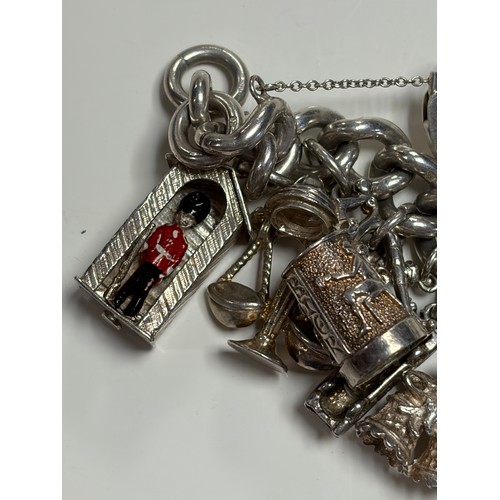 41 - A heavy silver charm bracelet, suspending an array of charms, including Big Ben and a top hat -