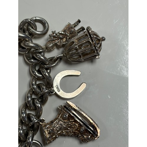 41 - A heavy silver charm bracelet, suspending an array of charms, including Big Ben and a top hat -